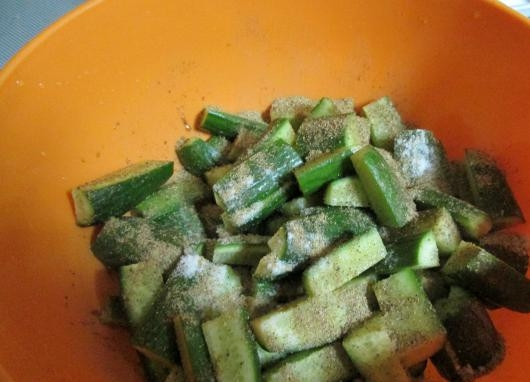 1. Этап. Огурцы с чесноком: Посыпаем порезанные огурцы солью и перцем. Перемешиваем.