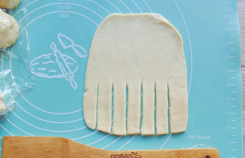 1. Этап. Булочки с яблоками и изюмом в духовке: Форму булочек определяйте сами, по своему желанию. У меня разные варианты. Опишу один из них. Раскатайте один шарик в пласт по форме, как на фото. С нижней стороны сделайте продольные надрезы где-то до средины пласта.