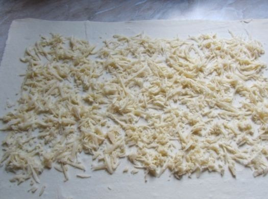 1. Этап. Мясной рулет в тесте: 4. Твердый сыр (лучше взять довольно соленый) натереть на терке и выложить ровным слоем на раскатанное тесто.