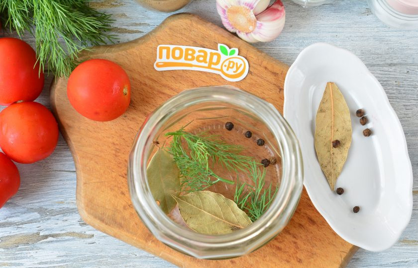 1. Этап. Маринованные помидоры с лимоном на зиму: На дно чистой простерилизованной банки выложите лавровый лист, перец горошком и немного укропа.