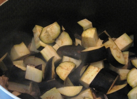 1. Этап. Баклажаны, жаренные со свининой: Нарезаем баклажаны, отправляем их к обжаренному мясу и слегка солим. Закрываем сковороду крышкой минут на 5-7, пусть баклажаны дадут сок.