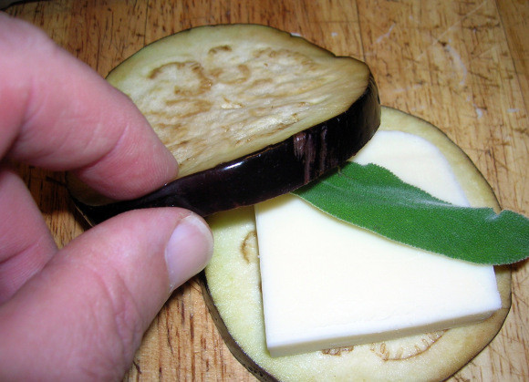 1. Этап. Баклажаны с сыром и чесноком: 4. Сыр порежьте кусочками, величиной с кружок баклажана. На баклажан выложите сыр, выдавите небольшое количество чеснока и веточку или листик зелени. Прикройте вторым кружочком баклажана.