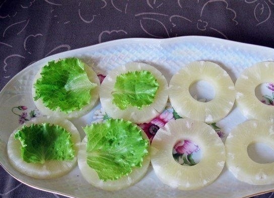 1. Этап. Ананасовая закуска: Разложите на блюде кружочки ананаса из банки. На каждый кружок положите по листику зеленого салата.