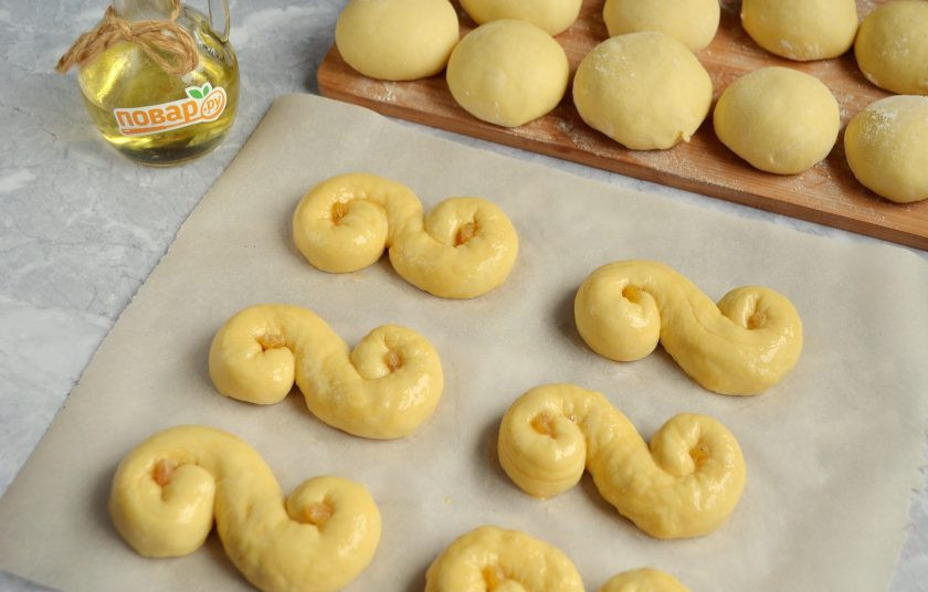 1. Этап. Золотые булочки: 8. Смажьте заготовки взбитым яйцом, положите в центры завитушек по изюминке (его нужно предварительно замочить в воде). Дайте расстояться в тепле 20 минут.