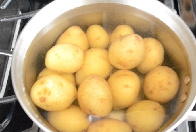 1. Этап. Картофельный салат с соусом Тцатцики: 1. Вымойте картофель небольших размеров, выложите в кастрюлю, залейте водой и отправьте на огонь. Отварите его до готовности.