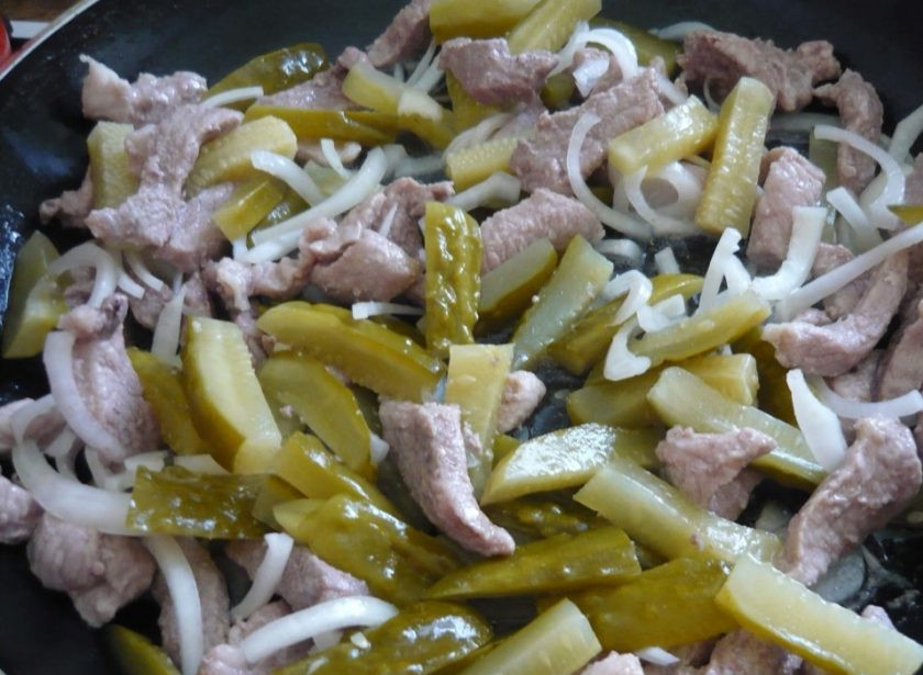 1. Этап. Азу из свинины: 5. В сковороду к обжаренному мясу добавьте огурцы и лук, перемешайте, накройте сковороду крышкой и готовьте на слабом огне.