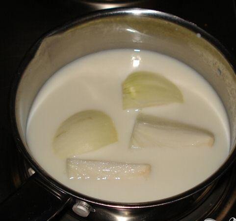 1. Этап. Выпечка из сыра и картофеля: Очистите и порежьте на четвертинки 1 лук. Поместите в молоко и доведите до кипения на среднем огне, затем добавьте лавровый лист. Затем процедите молоко (лук и лавровый лист больше не пригодятся). Залейте выпечку молоком и сверху посыпьте оставшимся тёртым сыром.