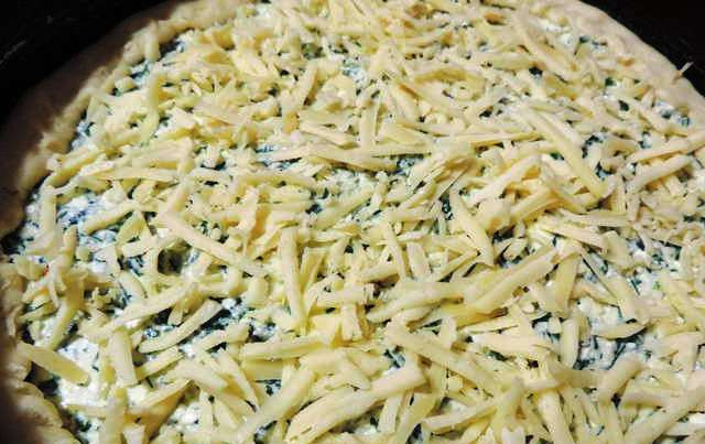 1. Этап. Пирог с зеленью: Форму для выпекания застелите пергаментом, выложите тесто, аккуратно распределите по поверхности и наколите вилкой. Затем выложите начинку, края теста загните на начинку и посыпьте тертым сыром. Поставьте в разогретую до 180 градусов духовку и выпекайте в течение 30 минут. Перед подачей на стол охладите до комнатной температуры.