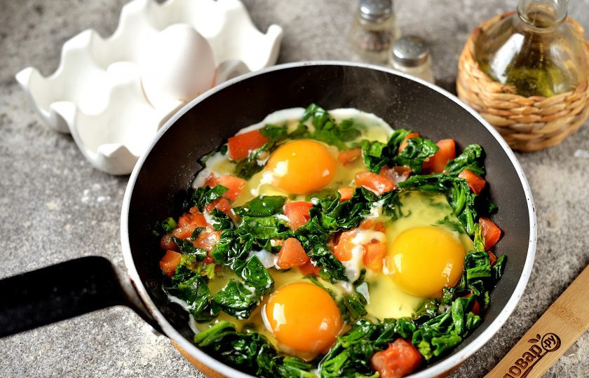 1. Этап. Яичница со шпинатом и помидорами: Через минуту-другую шпинат прилично уменьшиться в объеме. Отодвиньте шпинат с помидорами слегка в стороны, сделав лунки. В каждую лунку вбейте яйцо и жарьте яичницу на тихом огне, пока белок не приготовится полностью. Содержимое сковороды слегка посолите и поперчите.
