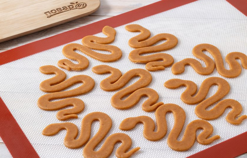 1. Этап. Имбирное печенье на Новый год Змеи: Выложите печенье на коврик для выпечки на небольшом расстоянии друг от друга. Выпекайте 5-7 минут в хорошо разогретой до 180 градусов духовке.