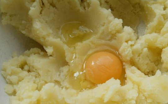 1. Этап. Ленивые картофельные вареники с грибами: В небольшую кастрюльку налейте чистую питьевую воду, поставьте ее на средний огонь, чтобы закипела. Картофель очистите от кожуры, вымойте и нарежьте на небольшие кусочки. Опустите картофель в кипящую воду, предварительно ее посолив. Варите его до готовности. Затем растолките картофель в пюре. Добавьте черный перец. Когда пюре немного остынет, вбейте в него сырое куриное яйцо и тщательно перемешайте ингредиенты.