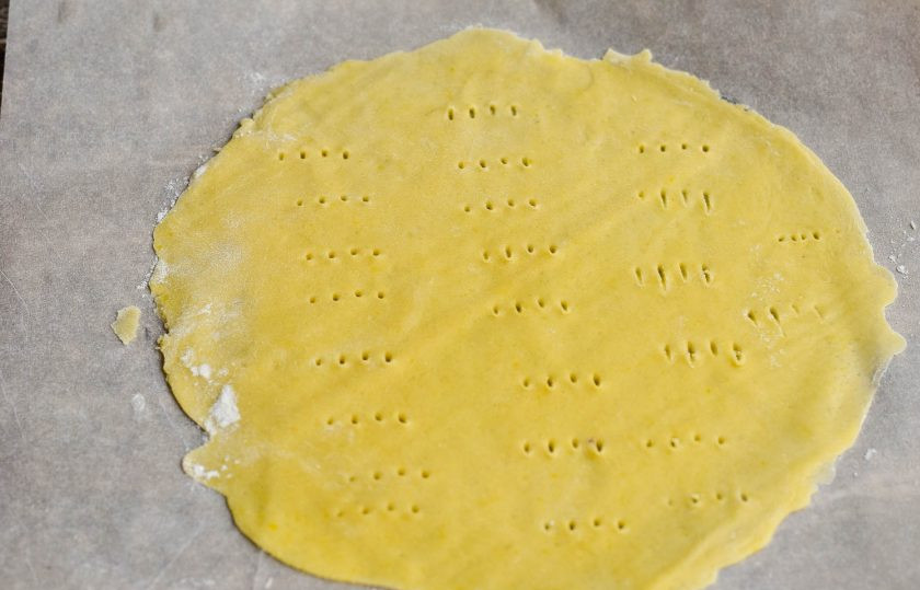 1. Этап. Медовик с бананом и киви: Поделите тесто на шарики. Возьмите один из них и раскатайте на пергаментной бумаге, на которой с обратной стороны нарисуйте ручкой круг, используя для помощи тарелку. Вилкой на корже сделайте проколы.