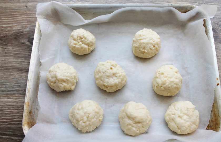 1. Этап. Сырные булочки без дрожжей: Застелите противень бумагой для выпечки, смажьте руки растительным маслом и сформируйте из теста одинаковые шарики. Выложите на противень на расстоянии.