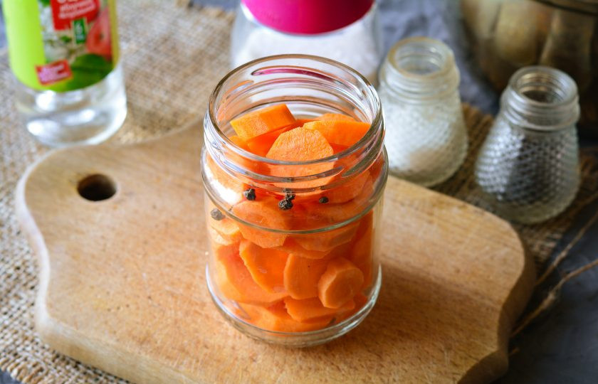 1. Этап. Консервированная морковь на зиму: Сложите в простерилизованную банку морковку и перец горошком.