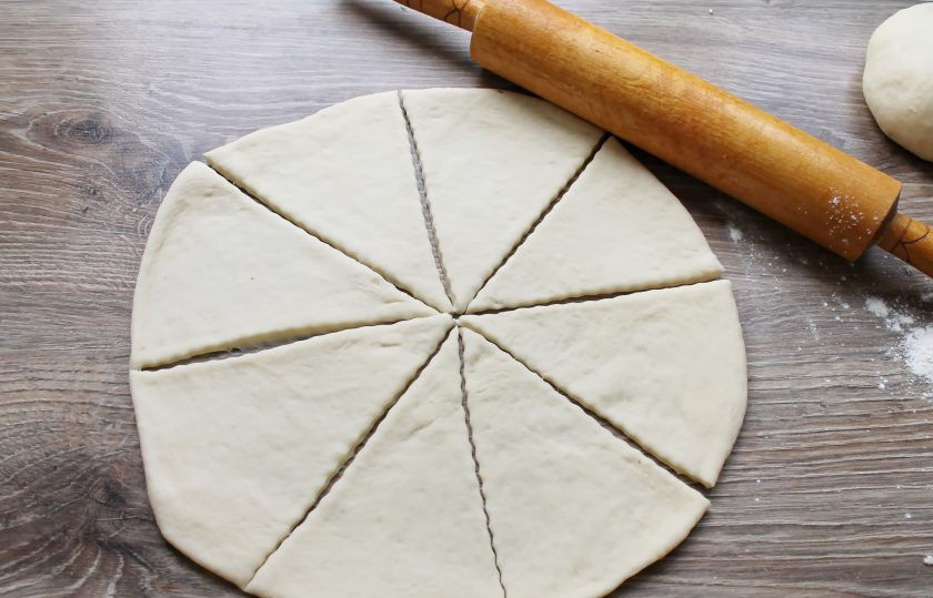 1. Этап. Рогалики в хлебопечке: Раскатайте каждую часть в круг толщиной 1 сантиметр. Разрежьте их на 8 равных сегментов.