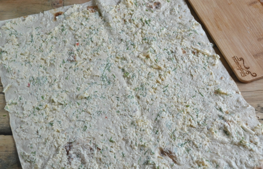 1. Этап. Лаваш с сыром и укропом: Ровным слоем намажьте сырную массу на лаваш, заверните его в рулет и оставьте минимум на 15 минут.