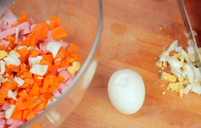 1. Этап. Новогодний венок из оливье: 1. Сначала приготовьте сам салат. Для этого нарежьте небольшими кубиками отваренный картофель, колбасу, отваренную морковь, яйца и все огурцы. Затем измельчите зелень и добавьте в салат.