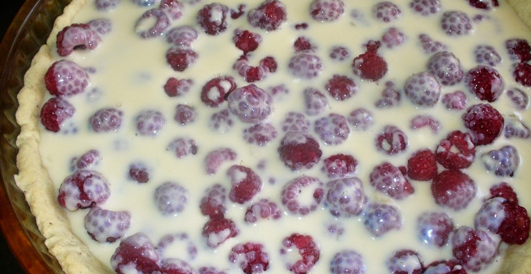 1. Этап. Пирог с малиной: 4. Сделаем теперь заливку. Ягодки отдельно перебираем и всыпаем на готовый корж. Для заливки же смешаем яйца, сметану, белок, сахарный песок, муку и ванильный сахар. Слегка взбиваем, заливаем ягоды. Отправим теперь запекаться еще на полчаса при той же температуре.