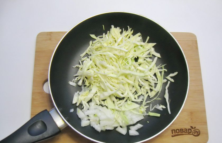 1. Этап. Пирог с белой рыбой: Пока тесто подходит, приготовьте начинку. Капусту нарежьте произвольно. Можно соломкой, можно кубиками. Выложите в сковороду. Добавьте нарезанный репчатый лук.