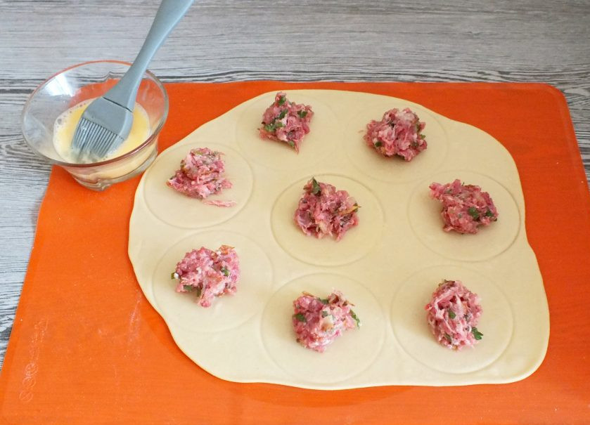 1. Этап. Мантапур: Раскатайте каждую часть в пласт толщиной 2-3 мм. Наметьте с помощью стакана (ориентировочно диаметр 8-9 см.) круги. На эти круги выложите по 1/2 ст.л. фарша. Свободное место вокруг фарша смажьте яйцом.