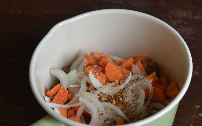 1. Этап. Свинина с ананасом: Морковь и лук вымойте, очистите. Нарежьте лук средними кубиками, а морковь — полукольцами. Добавьте овощи в сотейник к тушеному мясу, бросьте туда же специи и соль. Перемешайте.