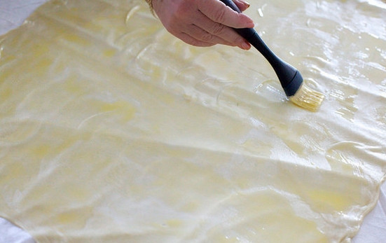 1. Этап. Штрудель с яблоком: 7. Растопите оставшееся масло и остудите. С помощью кисточки промажьте тесто примерно половиной масла.
