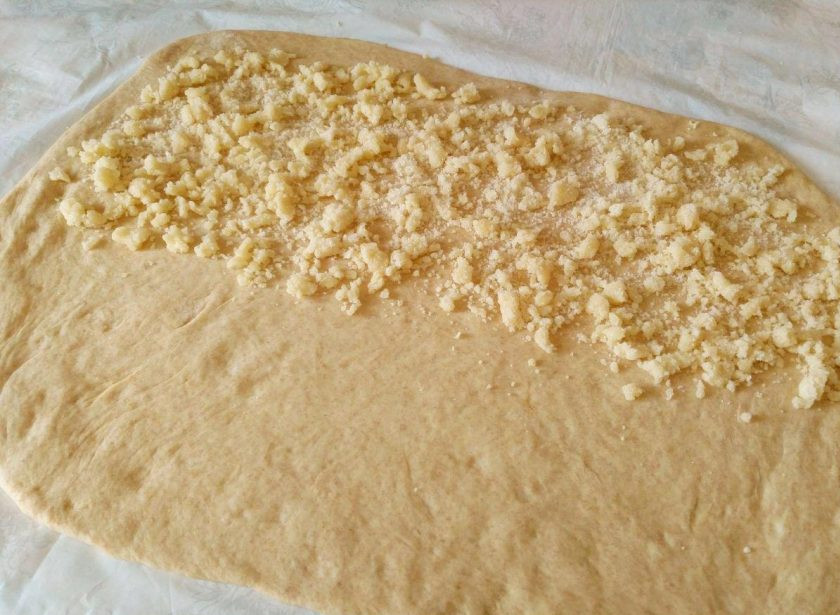 1. Этап. Сдобные булочки, прослоенные штрейзельной крошкой: Раскатайте тесто в прямоугольный пласт толщиной 4-5 мм и распределите на одной из его половин часть приготовленной крошки.