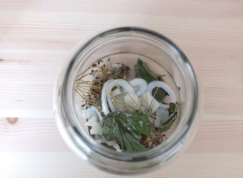 1. Этап. Помидоры резаные на зиму: В стерилизованную банку выложите: зонтик укропа, смородиновые листья, 3-4 колечка лука, разрезанный на пластинки чеснок, перец и уксусную эссенцию.