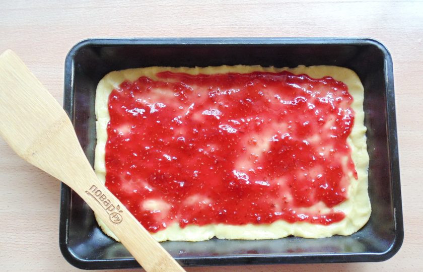1. Этап. Песочный пирог с малиновым вареньем: На тесто в форме выложите малиновое варенье.