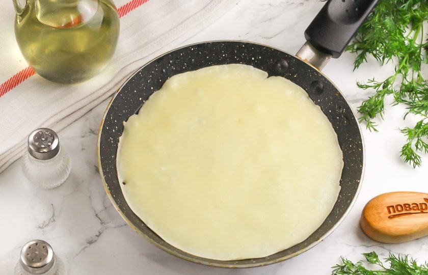 1. Этап. Блинные рулетики с начинкой: Сковороду, а еще лучше — две сковороды прогрейте на плите и смажьте растительным маслом. Влейте на каждую небольшую часть теста и округлите. Испеките блин 1-2 минуты с одной стороны.