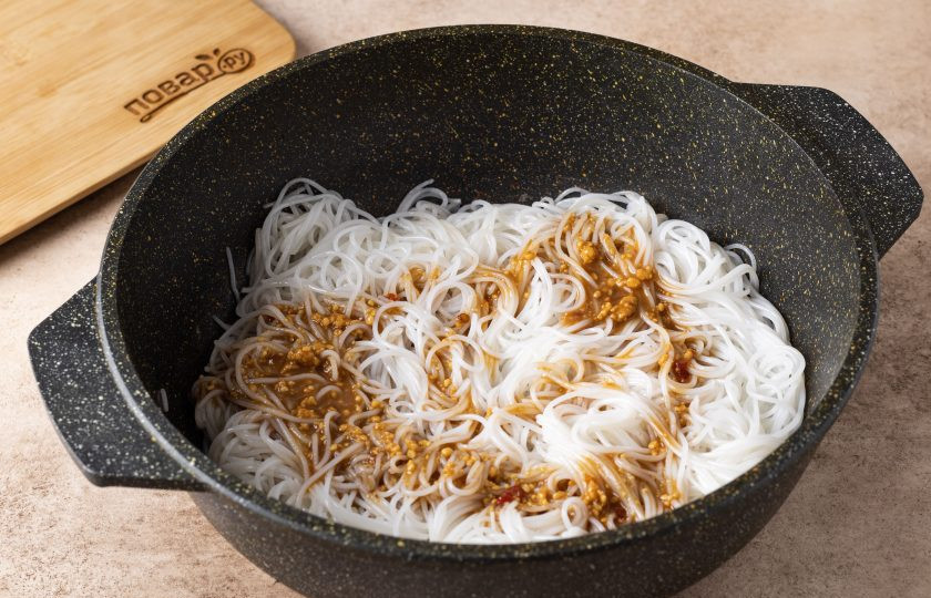 1. Этап. Тайское блюдо из рисовой лапши: Смешайте воду с арахисовой пастой до однородности, добавьте соевый соус и сладкий чили, перемешайте. Выложите в сковороду рисовую лапшу, немного обжарьте и заправьте соусом. Перемешайте, чтобы он равномерно распределился.