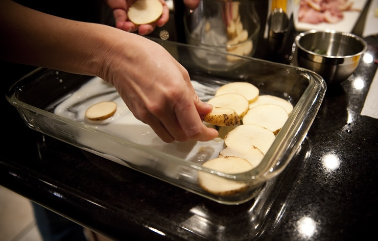 1. Этап. Картофельная запеканка с беконом: Прежде чем выкладывать картофель, поливаем тонким слоем противень готовым соусом. Сверху выкладываем один слой картофеля.