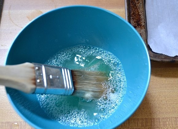 1. Этап. Хлеб с семечками: 11. Взбейте белок со столовой ложкой воды, смажьте обильно каждый хлебушек и сделайте крестообразные надрезы.