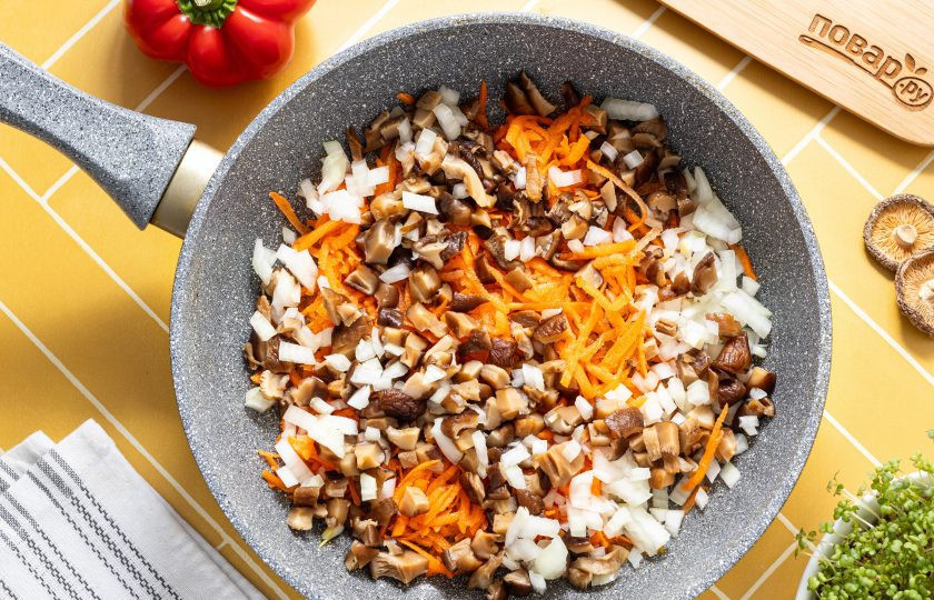 1. Этап. Овощные дамплинги: Нарежьте репчатый лук и вареные шиитаке мелкими кубиками, а морковь натрите на терке. На среднем огне обжарьте все вместе около 5 минут до золотистого цвета.