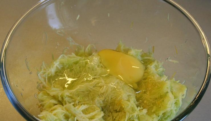1. Этап. Кабачковые оладьи сладкие: К натертым на терке кабачкам вбейте сырое куриное яйцо. Снова все перемешайте, чтобы масса получилась однородной.