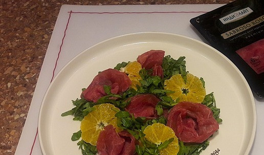 1. Этап. Новогодний салат мандариновый с сыровяленой индейкой: На тарелку положить рукколу, мандарины, мяско индейки свернув тонкие кружки нарезки в розочки