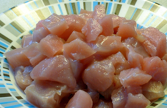 1. Этап. Куриная грудка с картошкой в духовке: 2. Первым делом вымыть и обсушить грудку. Нарезать ее средними кубиками. Чем мельче будут порезаны все ингредиенты, тем быстрее будет готово блюдо.