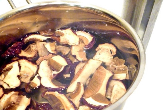 1. Этап. Сушеные грибы в горшочках: Сушёные грибы замочите в 600 мл холодной воды на 40 минут. Затем промойте их и переложите в кастрюлю. Залейте грибы водой, в которой они стояли. Доведите воду до кипения, снимите пену, потом уменьшите огонь и варите грибы под крышкой 20 минут, посолив.