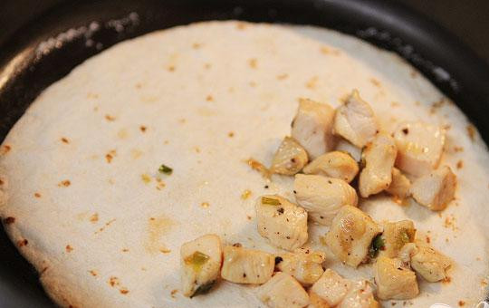 1. Этап. Кесадильяс с курицей, беконом и авокадо: 4. Добавить 1/2 столовой ложки сливочного масла в сковороду, нагреть на среднем огне. Выложить лепешку, а в центр поместить кусочки курицы, бекон, авокадо и немного сыра.