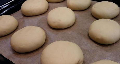 1. Этап. Ватрушки с повидлом: Поднявшееся тесто немножко подминаем и делим на части. У меня получилось 11 больших кусочков. Делаем шарики, немного примяв, выкладываем их на противень, застеленный бумагой. Накрываем полотенцем и оставляем на 15 минут.