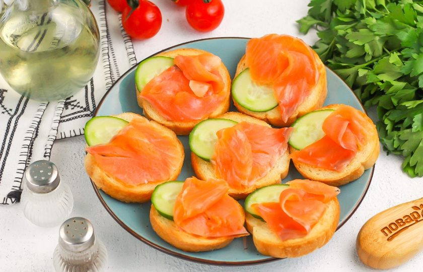 1. Этап. Брускетты в аэрогриле: Нарезку семги выложите сверху, слегка подворачивая ее, чтобы брускетты смотрелись аппетитнее.