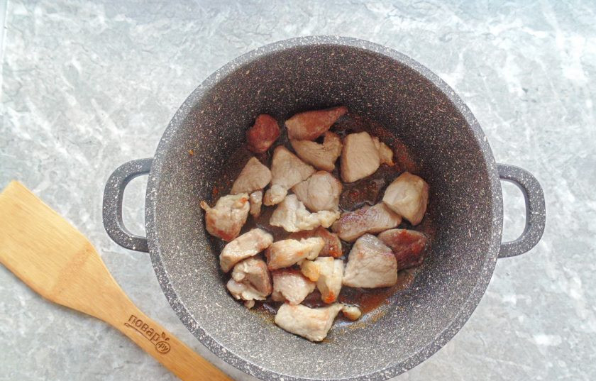 1. Этап. Мясо с капустой и яблоками: Тушите мясо в казане на среднем огне до золотистой корочки.