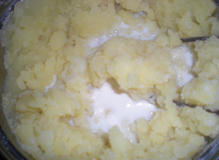1. Этап. Картофельное пюре без масла: Из кастрюли слейте всю воду. Поставьте её на медленный огонь, влейте молоко. Дождитесь, пока оно закипит. Затем при помощи толкушки сделайте пюре. По вкусу добавьте соль.