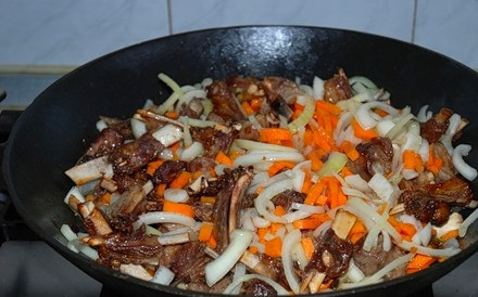 1. Этап. Бараньи ребрышки жареные: 5. Самое время отправить к мясу овощи. Вначале добавить лук, а через 3-5 минут - морковь. Все тщательно перемешать. Посолить и поперчить по вкусу, приправить базиликом, зирой, кориандром. Жарить на среднем огне около 15 минут.