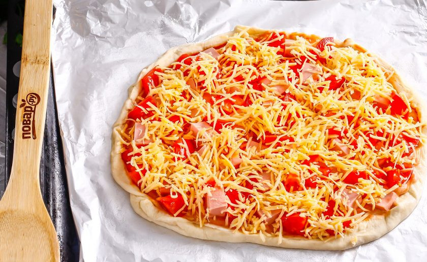 1. Этап. Пицца Мужская: Сверху выложите тертый сыр. Разогрейте духовку до 200 градусов и поместите в нее заготовку пиццы. Испеките примерно 15-20 минут до готовности теста.