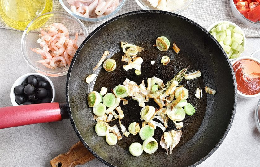 1. Этап. Рагу из морепродуктов: Выложите лук-порей, нарезанный кружочками. Жарьте пару минут, помешивая.