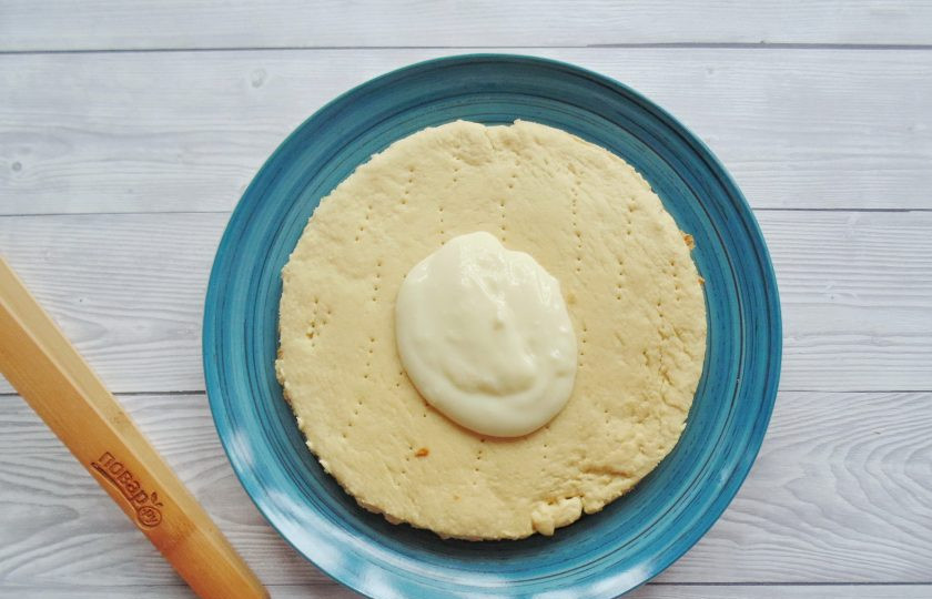 1. Этап. Медовый торт с вишней: Сборка торта. Выложите первый корж на блюдо, смажьте кремом.