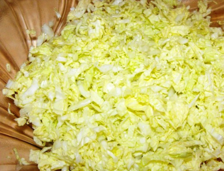 1. Этап. Салат из кальмаров с овощами: Пошинкуйте капусту и помните её руками.