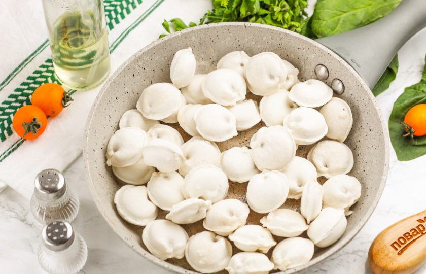 1. Этап. Пельмени с помидорами на сковороде: Прогрейте в сковороде растительное масло и выложите в нее замороженные пельмени. Заранее их размораживать не нужно!