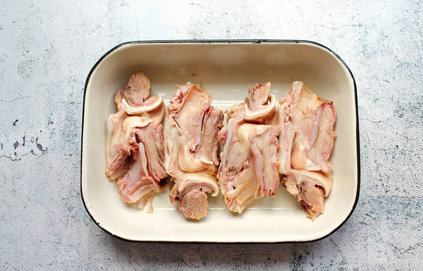 1. Этап. Фаршированные свиные калтыки: Разрежьте калтыки вдоль на две части и выложите в форму для запекания.